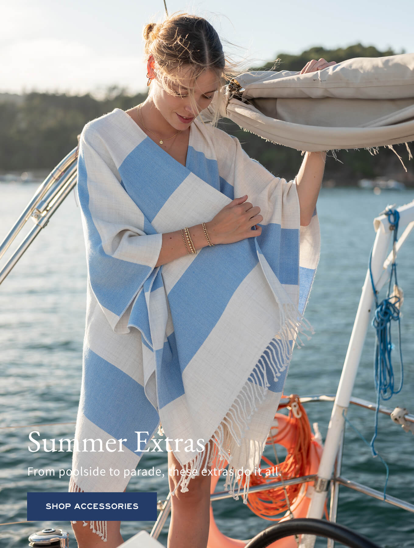 A woman in a large blue and white striped wrap over a bikini on a boat, with bracelets on her wrist.