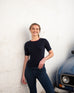 woman wearing mersea acton rib knit navy top standing against white wall
