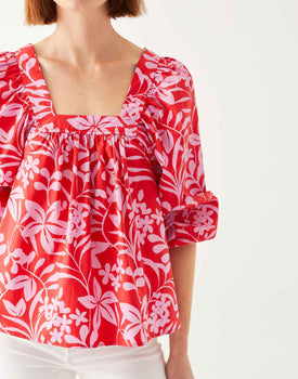 female wearing red poplin top with pink floral on a white background