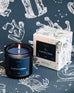 Mersea Capricorn scented candle displayed beside its accompanying box, set against an astrology sign-themed backdrop