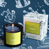 Mersea Gemini scented candle displayed beside its accompanying box, set against an astrology sign-themed backdrop