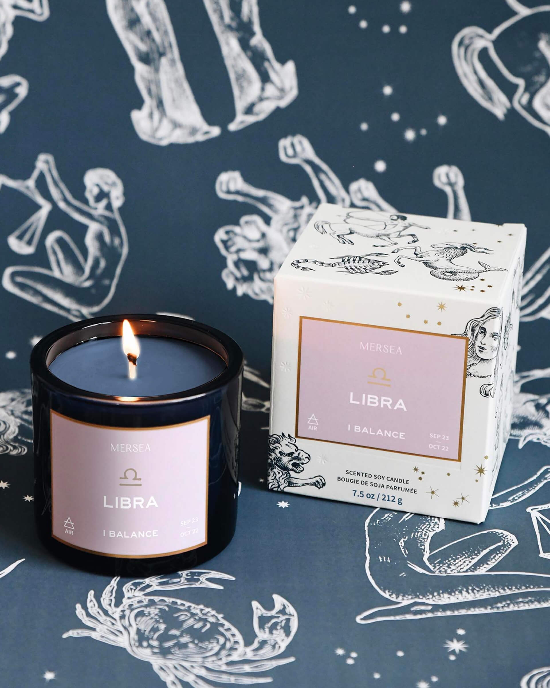 Mersea Libra scented candle displayed beside its accompanying box, set against an astrology sign-themed backdrop