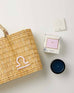 Mersea Libra candle next to candle box and medina bag on white background