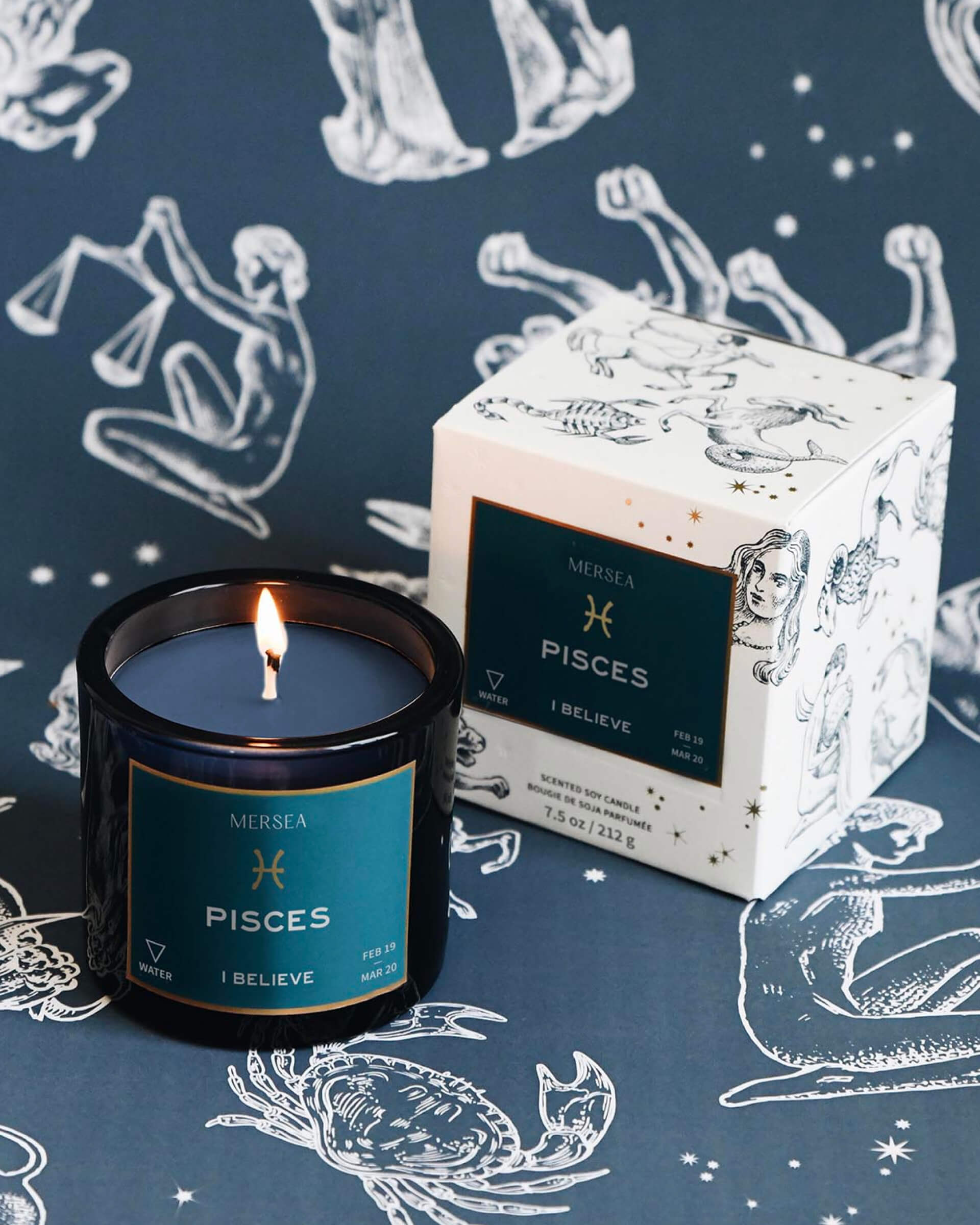 Mersea Pisces scented candle displayed beside its accompanying box, set against an astrology sign-themed backdrop
