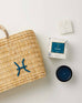 Mersea Pisces candle next to candle box and medina bag on white background
