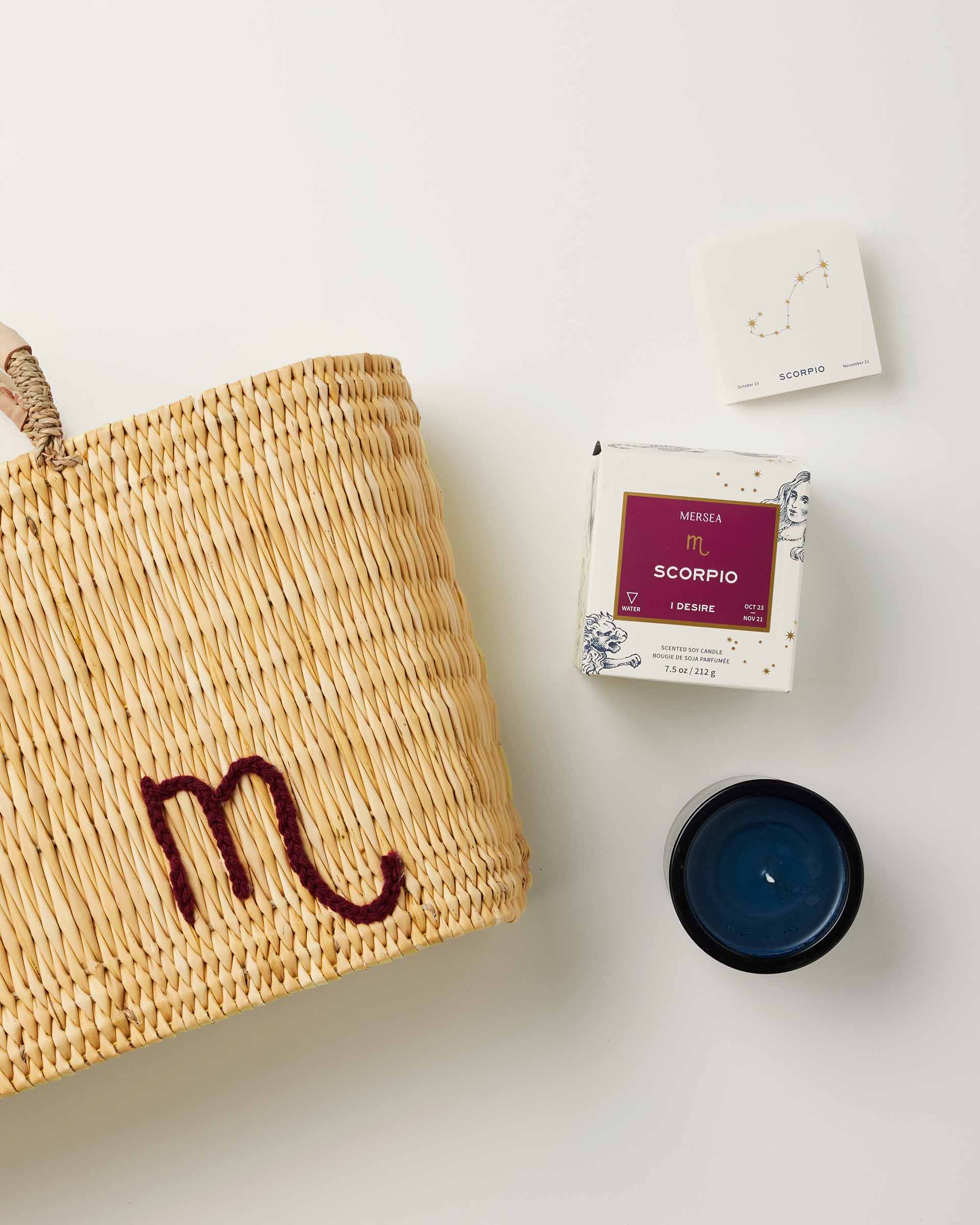 Mersea Scorpio candle next to candle box and medina bag on white background