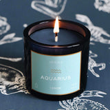 Mersea Aquarius scented candle displayed against an astrology sign-themed backdrop