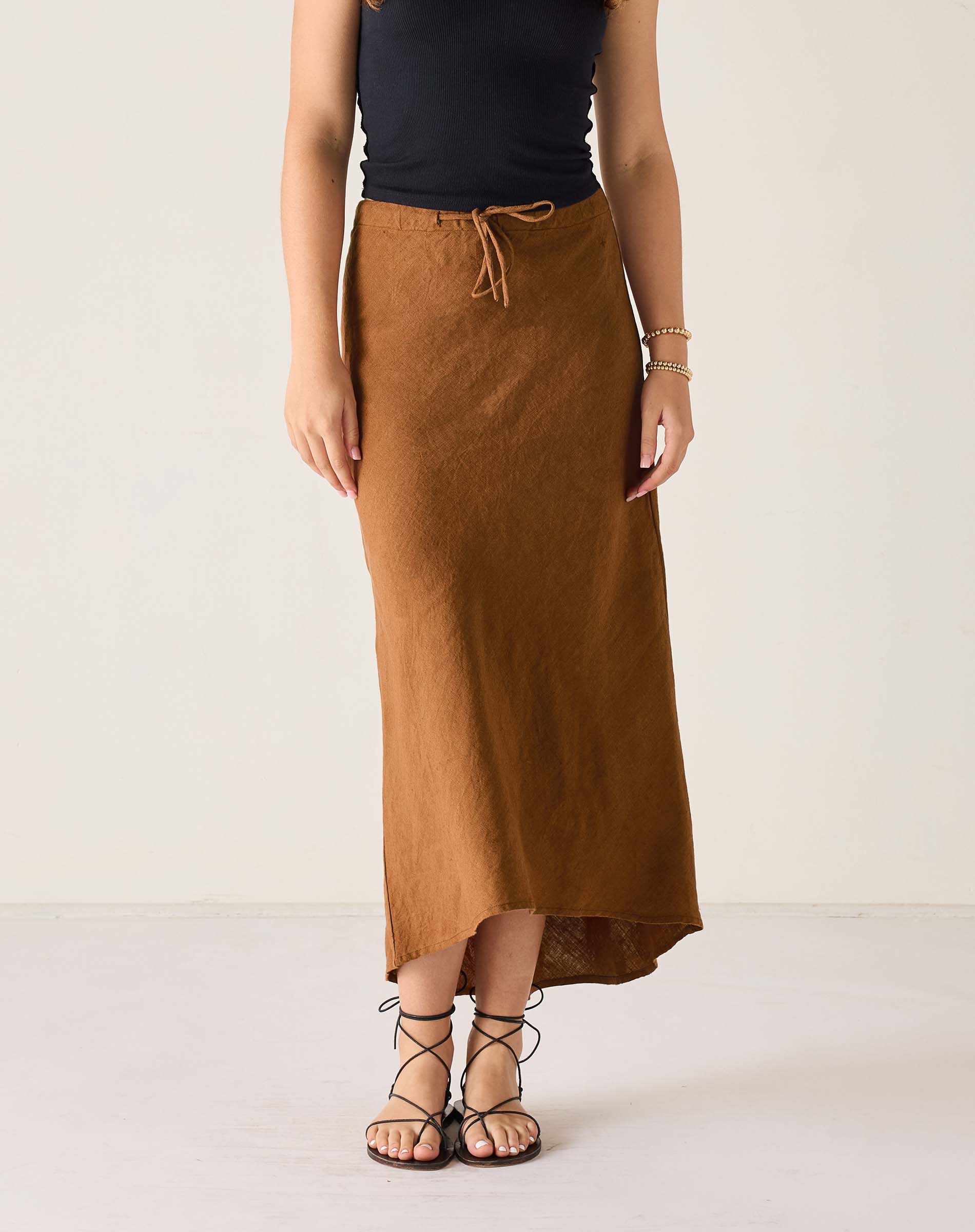 Person wearing a brown skirt and black top on a white background