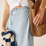 Person holding a woven bag and a knitted item against a neutral background