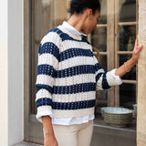 Woman wearing a blue and white striped sweater in an urban setting.