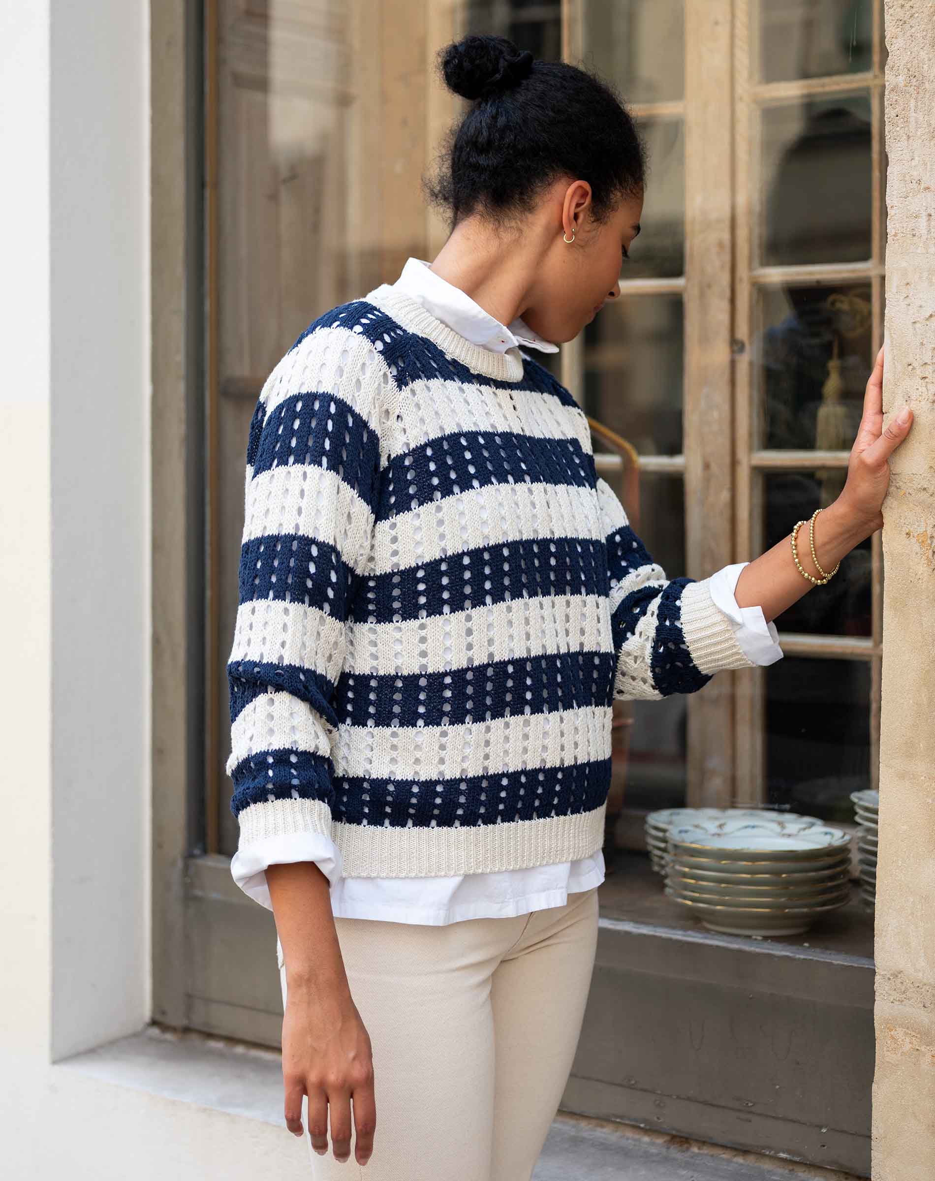 Woman wearing a blue and white striped sweater in an urban setting.