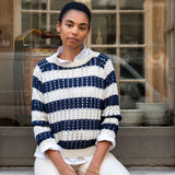 Woman wearing a navy and white striped sweater sitting in front of a window.