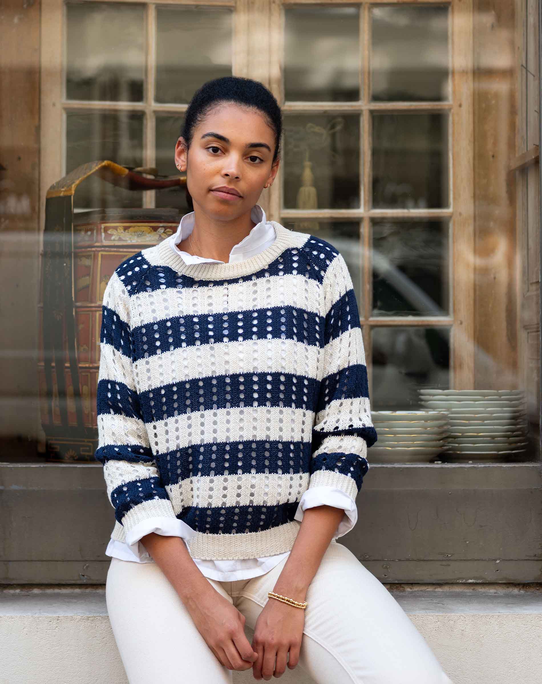 Woman wearing a navy and white striped sweater sitting in front of a window.