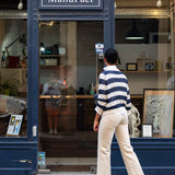 Person walking past a store named 'Atelier ManuFact' with art displayed inside.
