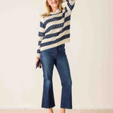 Woman wearing a striped sweater and jeans against a plain background