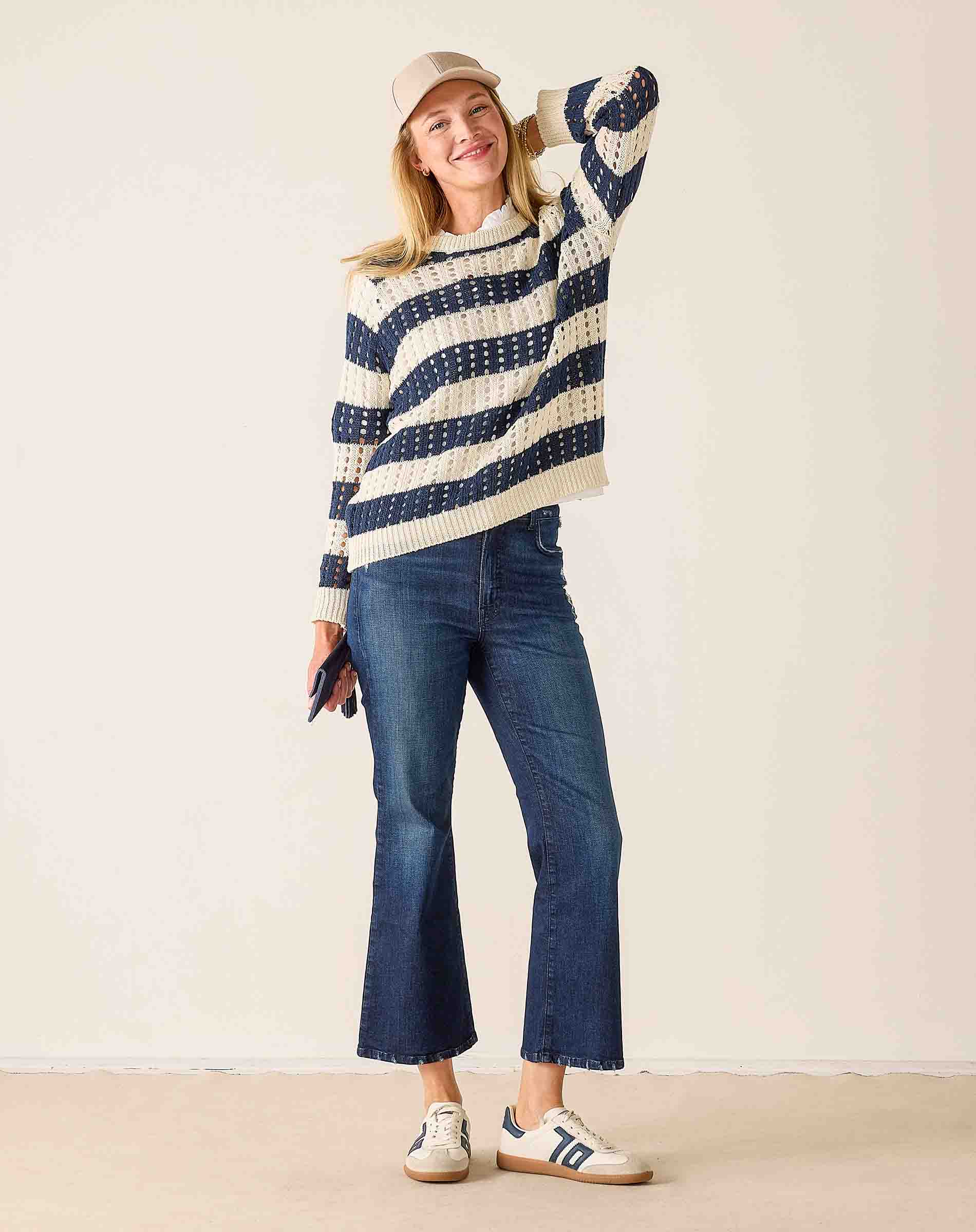 Woman wearing a striped sweater and jeans against a plain background