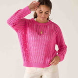 Woman wearing a bright pink knitted sweater against a white background