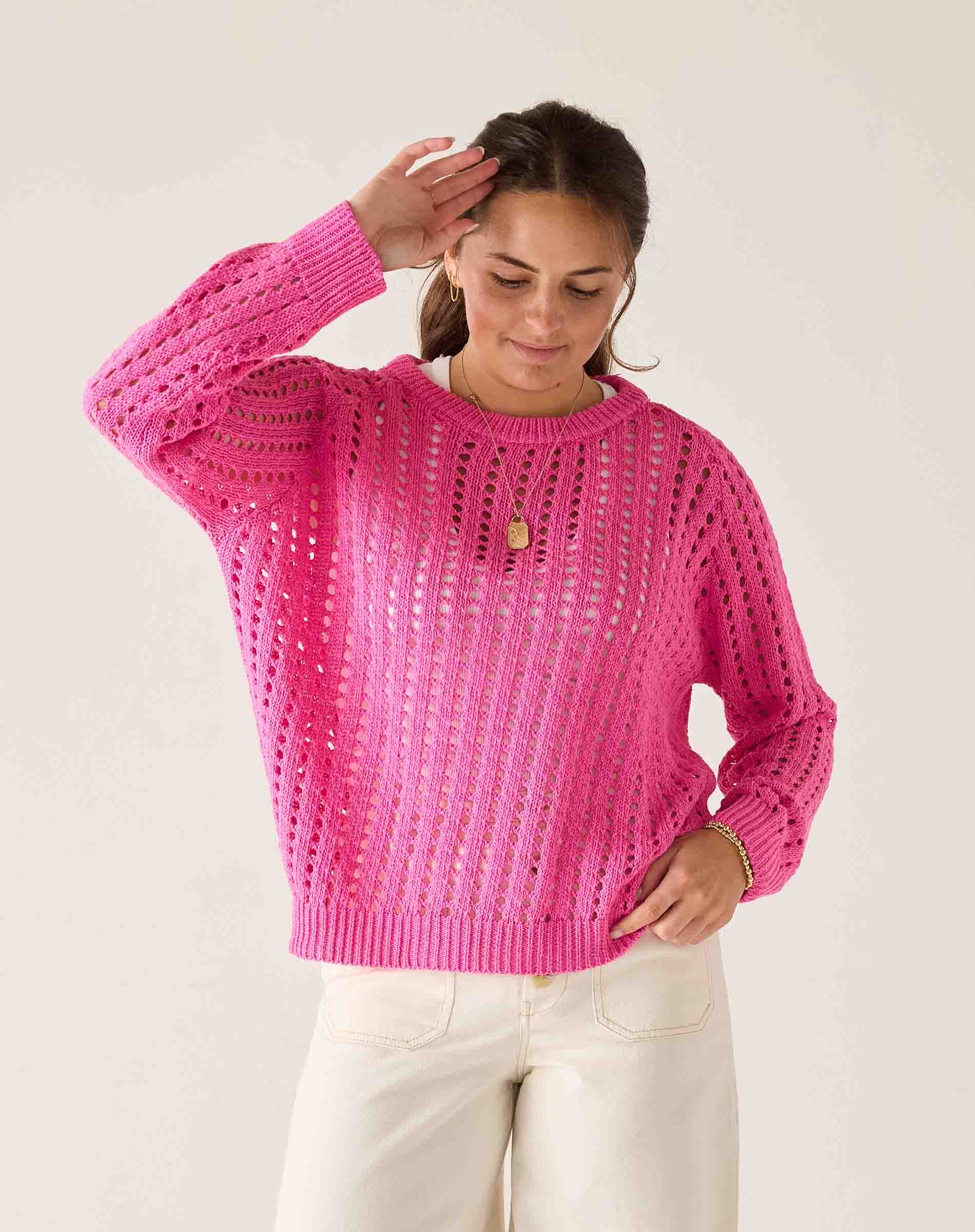 Woman wearing a bright pink knitted sweater against a white background