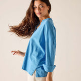 Woman wearing a blue shirt and white shorts against a plain background