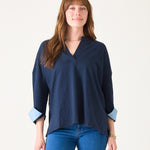 Woman wearing a navy blue blouse with rolled-up sleeves on a white background