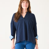Woman wearing a navy blue blouse with rolled-up sleeves on a white background