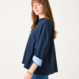 Woman wearing a navy blue top with rolled-up sleeves on a white background