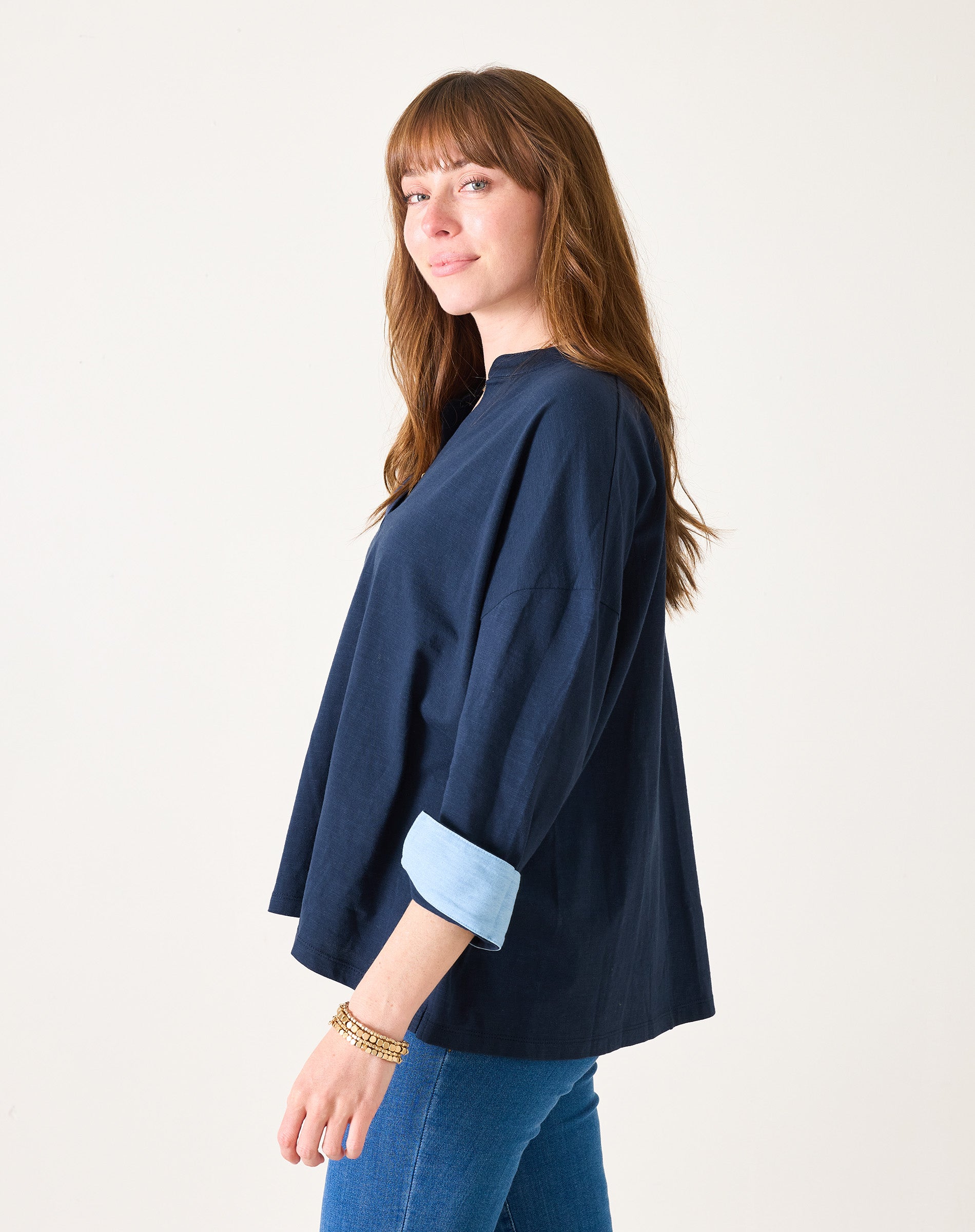 Woman wearing a navy blue top with rolled-up sleeves on a white background