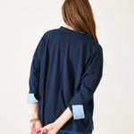 Woman wearing a navy blue cardigan with light blue cuffs and hem on a white background