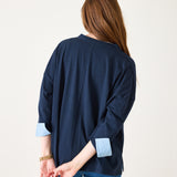 Woman wearing a navy blue cardigan with light blue cuffs and hem on a white background