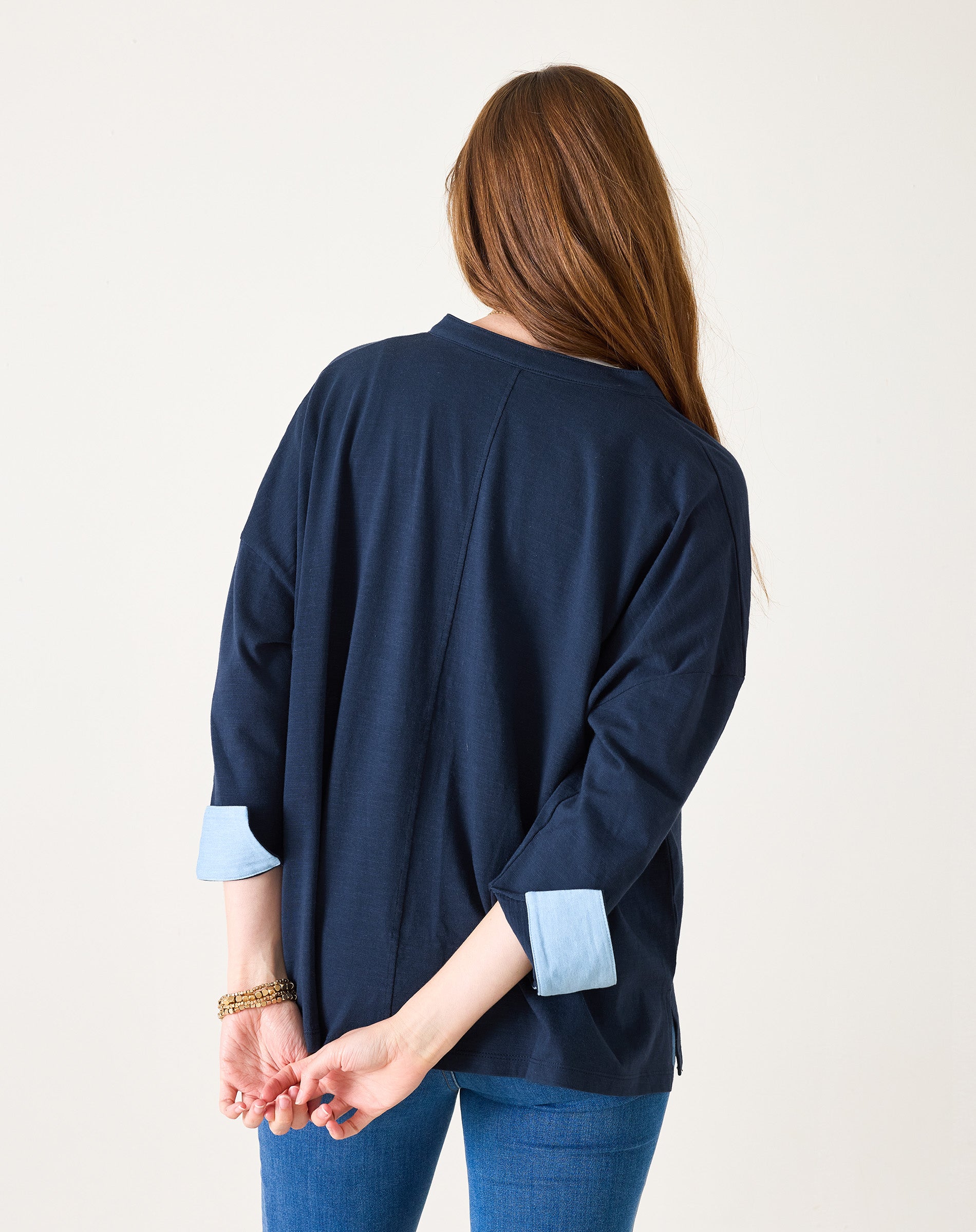 Woman wearing a navy blue cardigan with light blue cuffs and hem on a white background