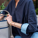 Person wearing a navy blue shirt with rolled-up sleeves, holding a gray bag.