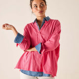Woman wearing a pink shirt with denim collar and cuffs against a beige background