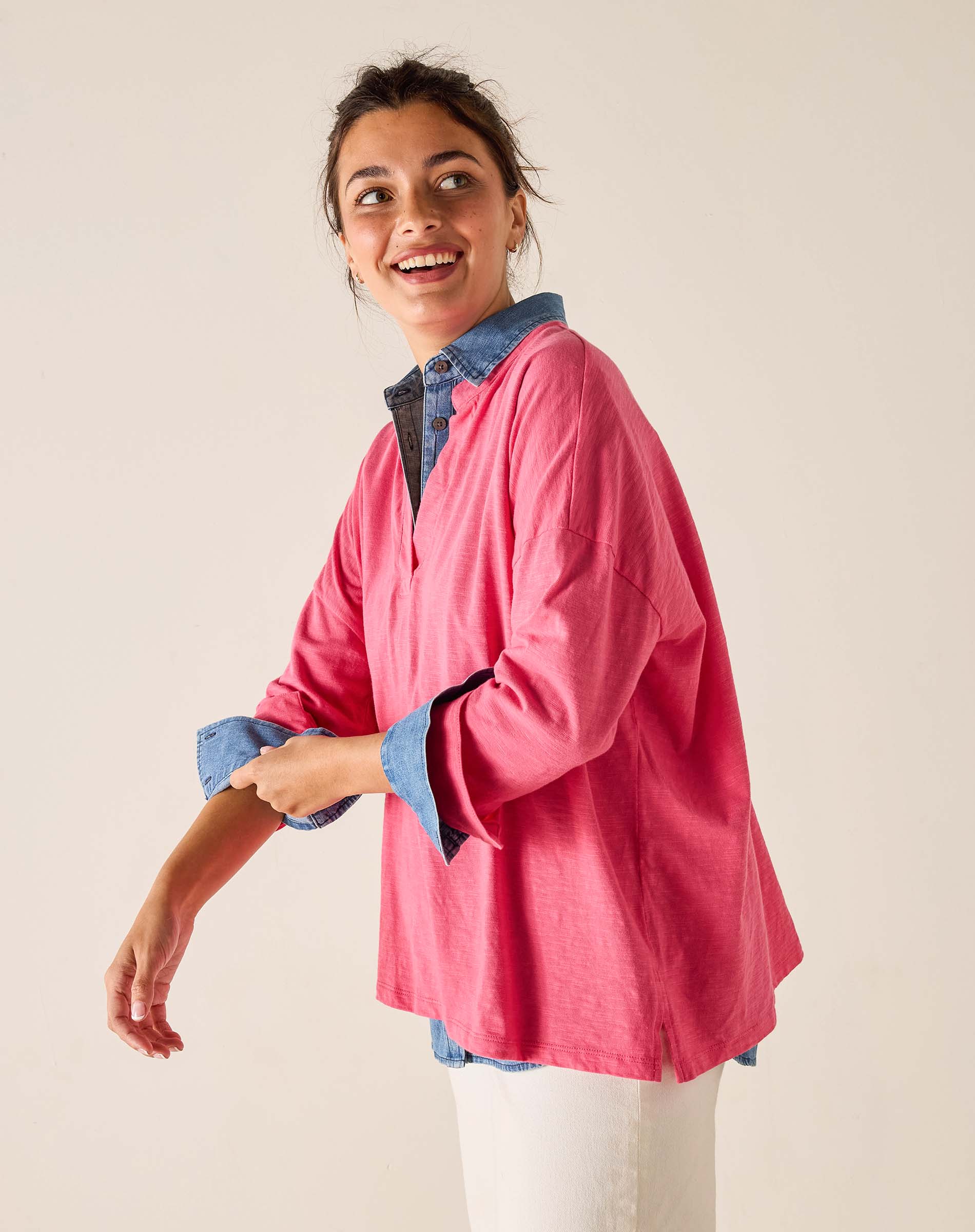 Woman wearing a pink shirt with denim sleeves against a beige background
