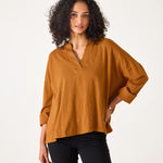 Woman wearing a mustard yellow blouse against a white background