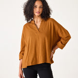 Woman wearing a mustard yellow blouse against a white background