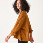Woman wearing a mustard yellow blouse against a white background
