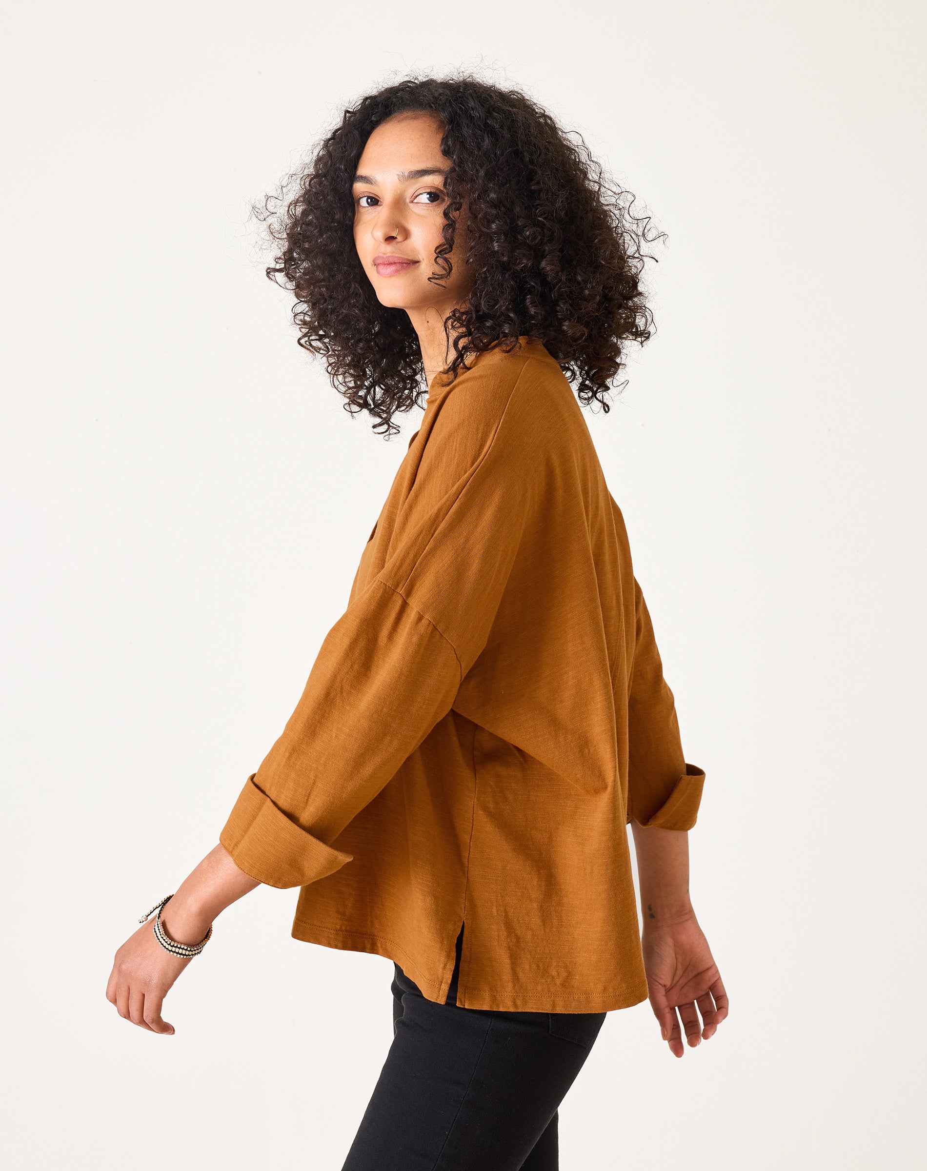 Woman wearing a mustard yellow blouse against a white background