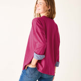 Woman wearing a magenta shirt and blue jeans on a white background