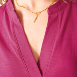Close-up of a person wearing a gold necklace with a pink top.