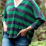 Person wearing a green and navy striped shirt with a blurred natural background