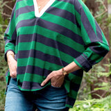 Person wearing a green and navy striped shirt with a blurred natural background