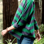 Person wearing a green and navy striped sweater in a forest setting