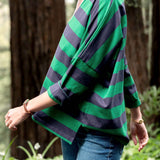 Person wearing a green and navy striped sweater in a forest setting