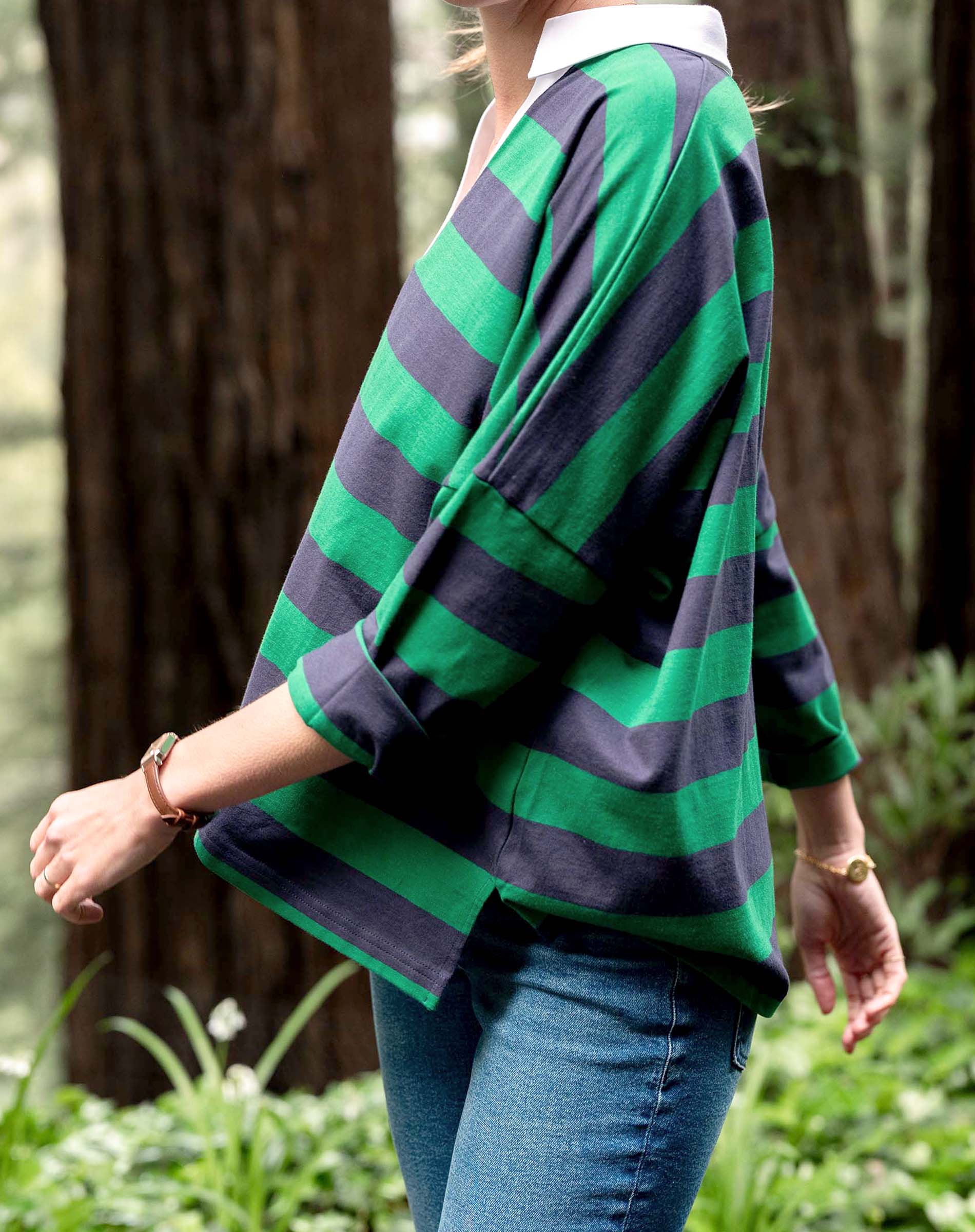 Person wearing a green and navy striped sweater in a forest setting