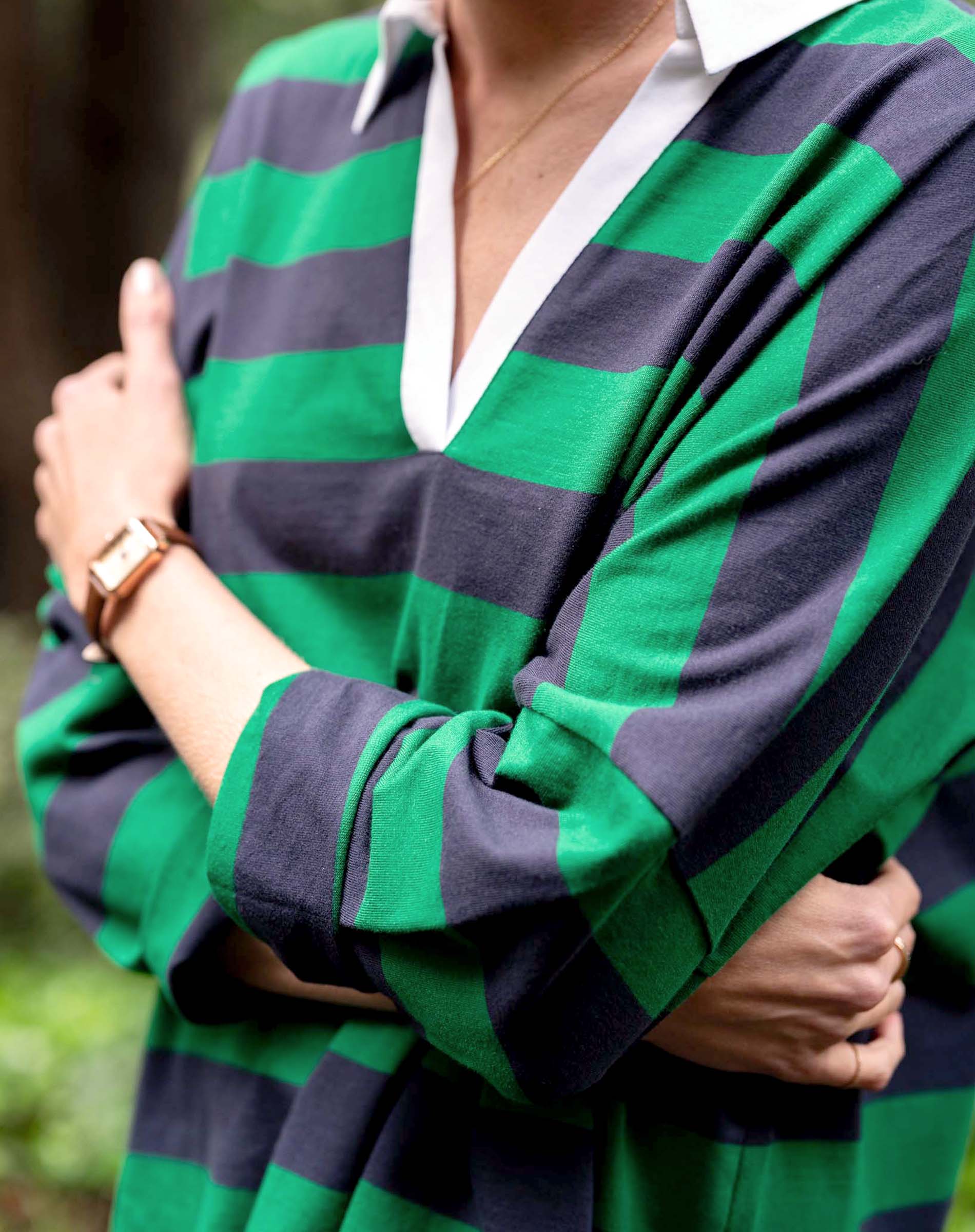 Person wearing a green and navy striped shirt with a blurred background