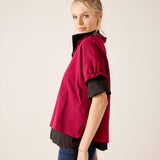 Berry ruffled tee in a tiered style over a black base layer, paired with blue jeans.