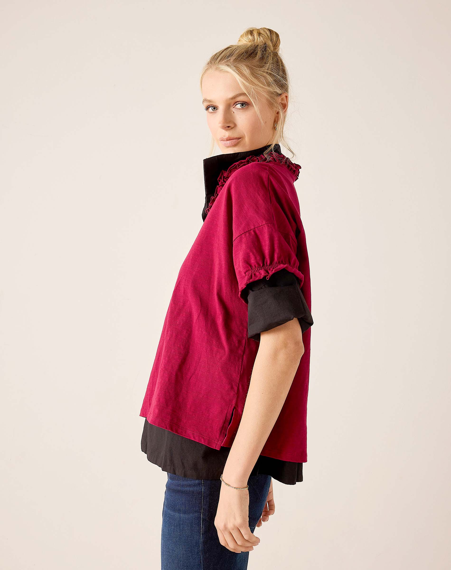 Berry ruffled tee in a tiered style over a black base layer, paired with blue jeans.