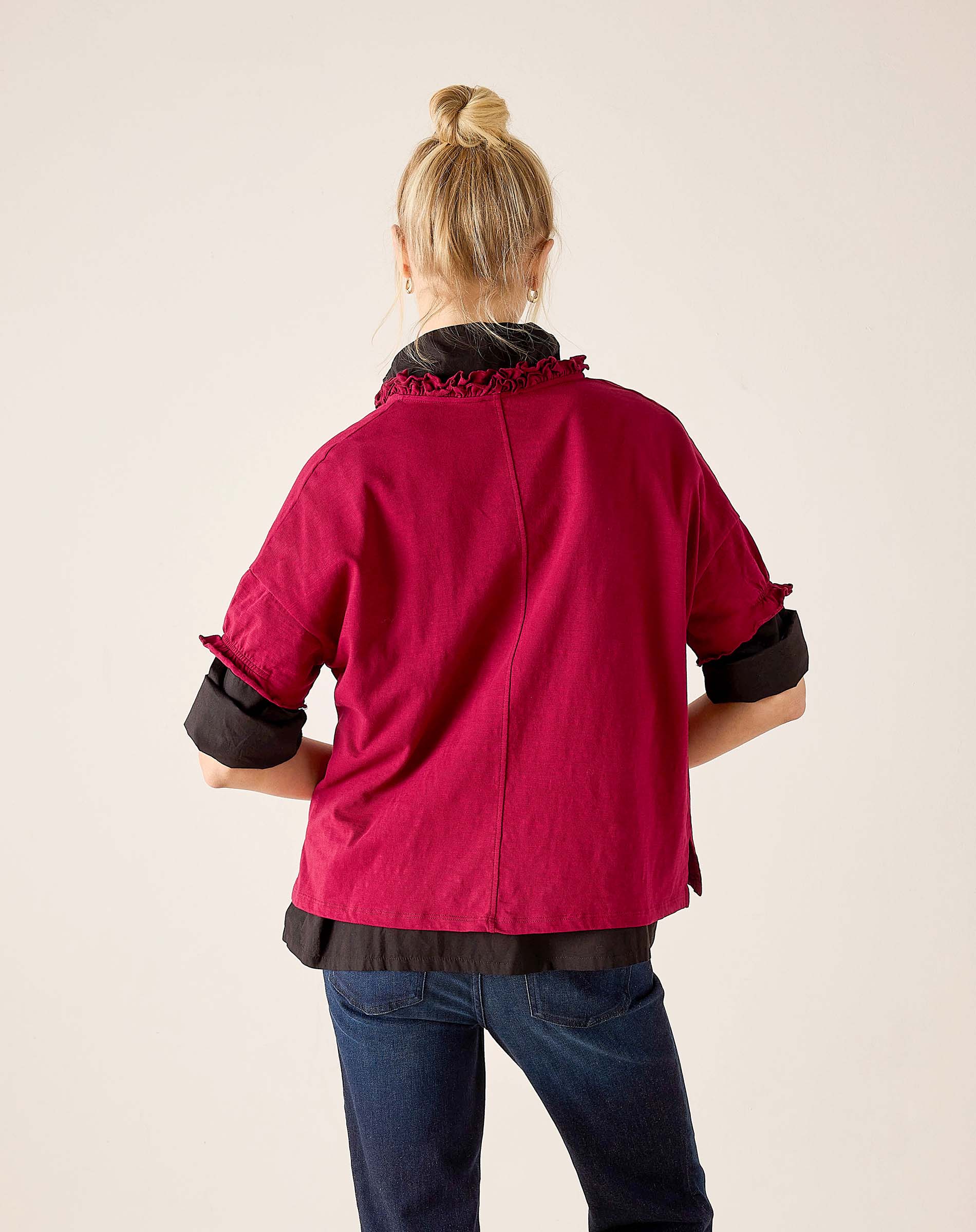 Back view of the berry ruffle tee with black trim and denim jeans.
