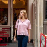 Woman walking past a cafe with red awning and chairs