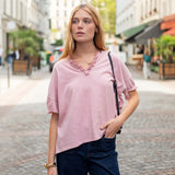 Woman wearing a pink blouse and dark pants on a city street
